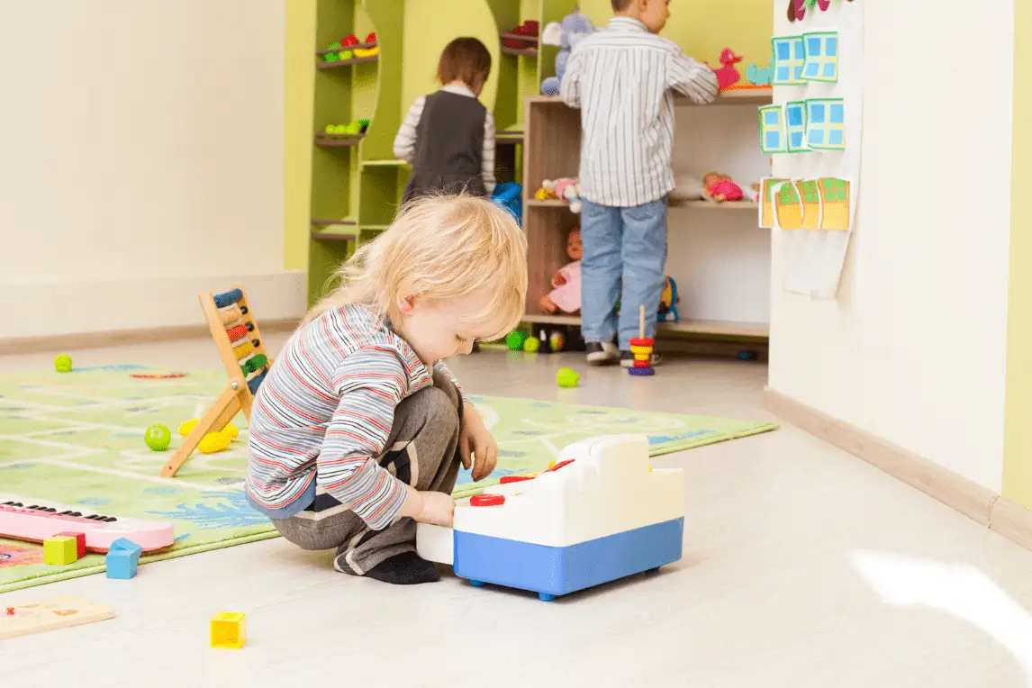 Kinder mit einer Kasse spielen in einem bunten Raum.